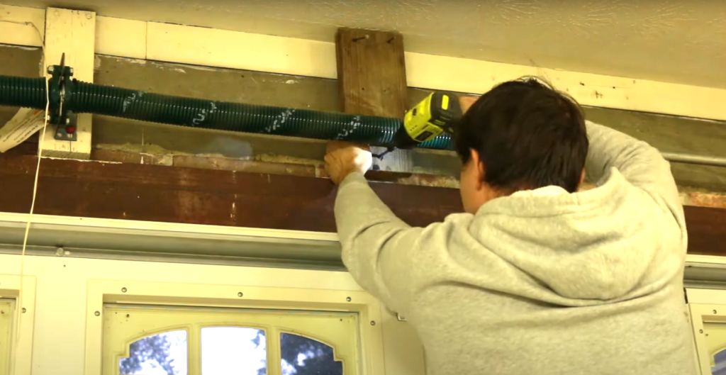 Technician performing garage door spring repair with precision tools in Florida